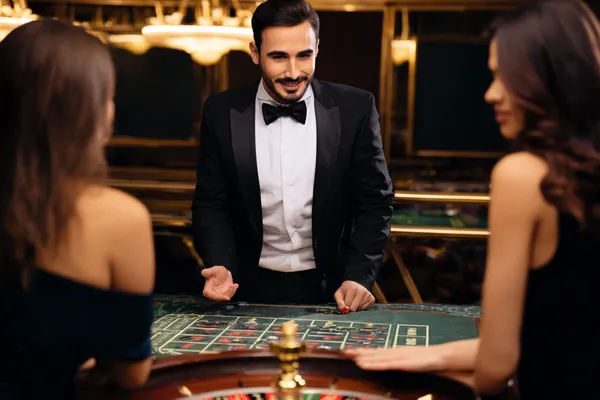 A professional dealer in a tuxedo greeting players at the roulette table, symbolizing the authentic live casino feel at K55GAME.